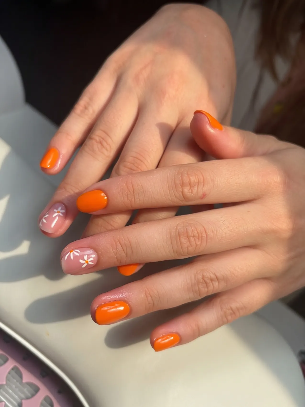 Ongles courts orange avec fleurs blanches peintes
